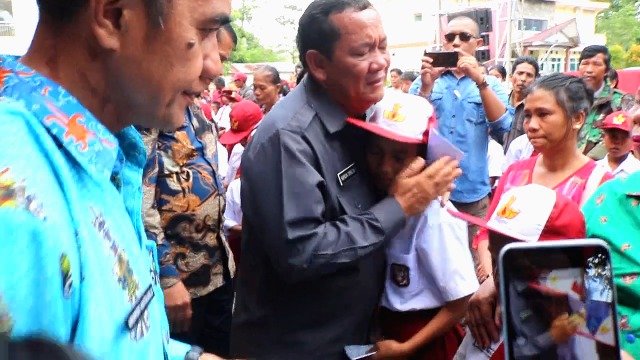 Bupati Samosir Rapidin Simbolon memeluk pelajar dan berikan bantuan beasiswa bagi yatim piatu. (mimbar/robin)