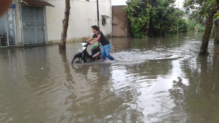 Warga mendorong sepeda motornya ditengah banjir di kawasan Medan Labuhan. (mimbar/budi)