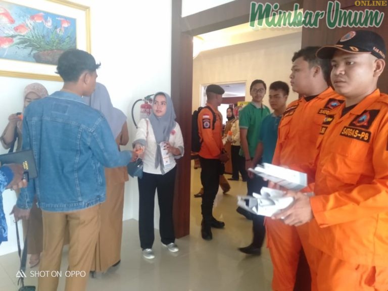 Satgas BPBD Paluta membagikan masker kepada peserta sesaat sebelum memasuki ruang rapat Musrenbang. (mimbar/lomo)