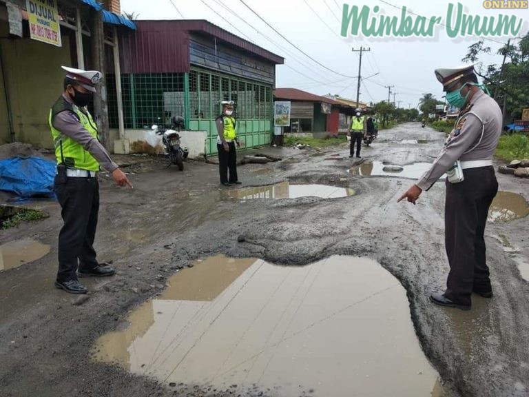 Petugas kepolisian meninjau Jalan Perintis Kemerdekaan/Besar Hamparan Perak yang rusak parah. (mimbar/ist)