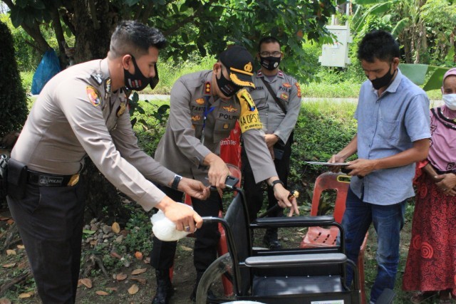 AKBP Eko Hartanto memberikan kursi roda pada saudari Mulina di Desa Cot Girek Kandang, Kecamatan Muara Dua. (ist)