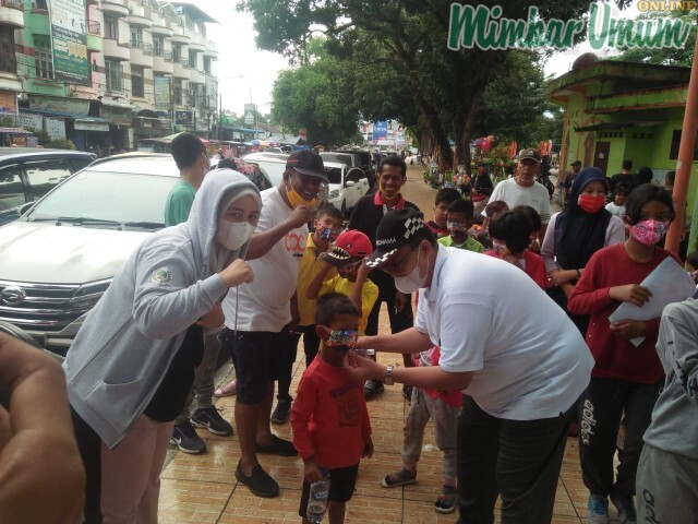 Juliadi memasangkan masker kepada anak kecil di lapangan Merdeka Binjai. (mimbar/burhan sinulingga)