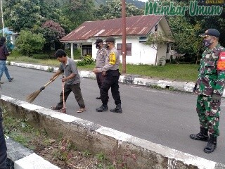 Warga menyapu jalan sebagai hukuman tidak memakai masker di Samosir. (Robin Nainggolan)