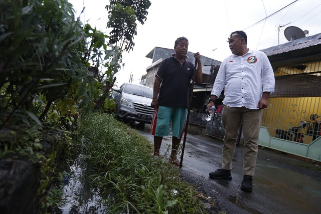 Aulia Rachman melihat warga Perumnas Helvetia bersihkan sampah dari aliran parit. (Ist)